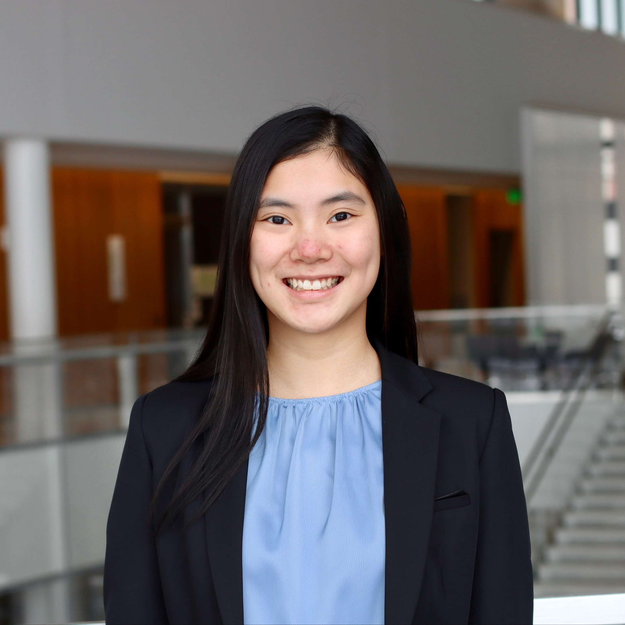 Asian female in a blue blouse and black jacket smiling